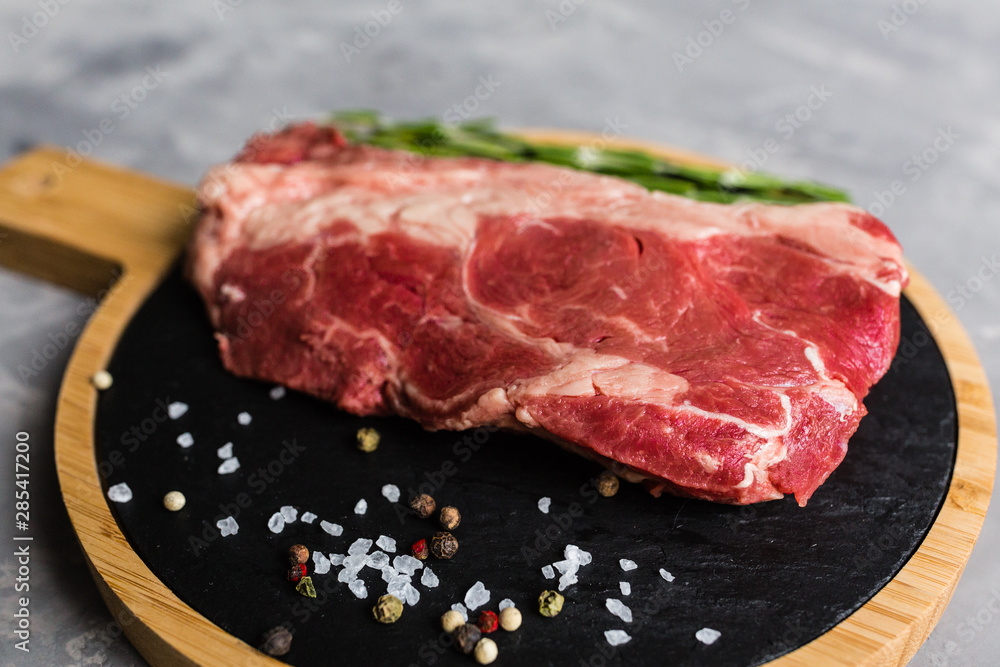 Raw meat beef on a cutting board with rosemary and spices. Top view, flat lay, mockup, copy space. Food concept