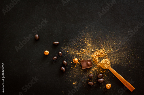 Chocolate with nuts and its ingredients on black background top view copyspace