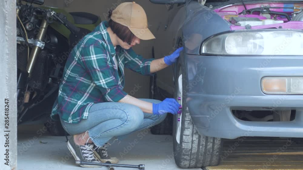 Female mechanic fixing car in a garage Female mechanic fixing car in a garage
