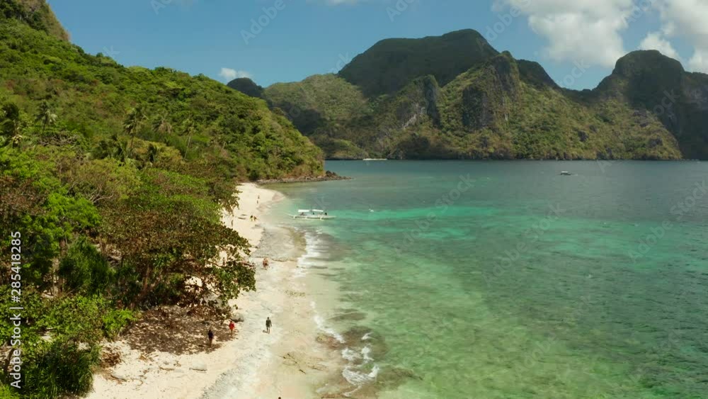 aerial view tropical beach on island with palm trees, blue lagoon and azure clear water. Helicopter Island in El Nido, Palawan Philippines. Tropical landscape with blue lagoon, coral reef