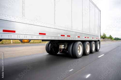 Big rig semi truck transports a heavy-duty four-axle semi trailer running on the highway