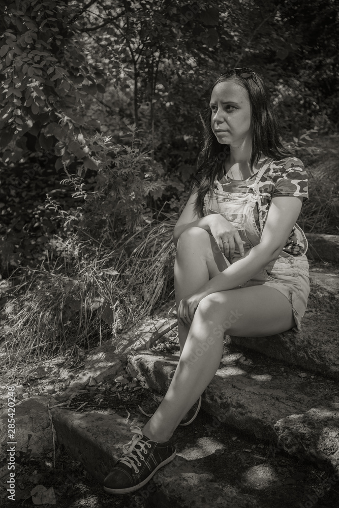 Sad woman sitting on the old steps in the Park, in black and white treatment. Female in sorrow Sad woman sitting on the old steps in the Park, in black and white treatment. Female in sorrow