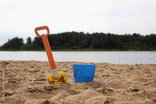 Baby shovel and bucket in sand on the river bank photo