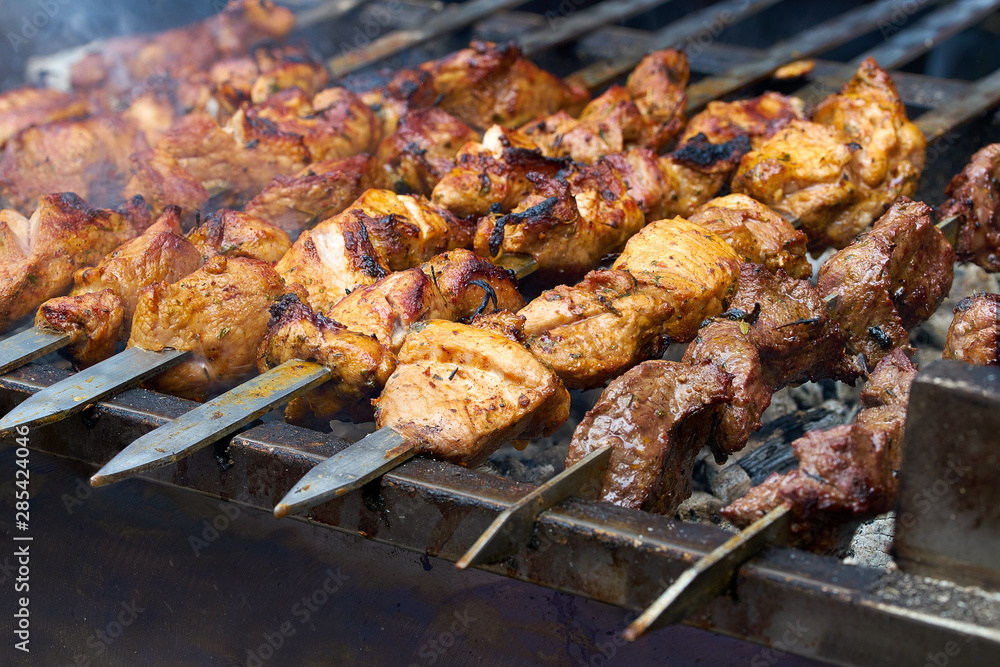 pieces of meat are friend on fire on skewers on grill. close up