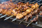 pieces of meat are friend on fire on skewers on grill. close up
