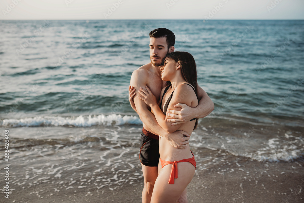 young couple hugging on the beach - love, couple, vacation and summer concepts young couple hugging on the beach - love, couple, vacation and summer concepts