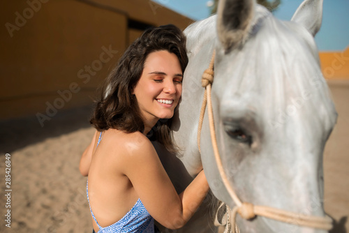 smiling woman hugging a white horse