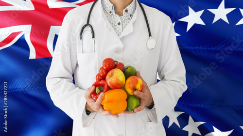 Doctor is holding fruits and vegetables in hands with Cook Islands flag background. National healthcare concept, medical theme.