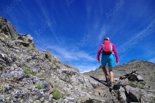 Jeune femme qui grimpe t marche en montagne avec ciel bleu et sac à dos