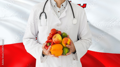 Doctor is holding fruits and vegetables in hands with Gibraltar flag background. National healthcare concept, medical theme.
