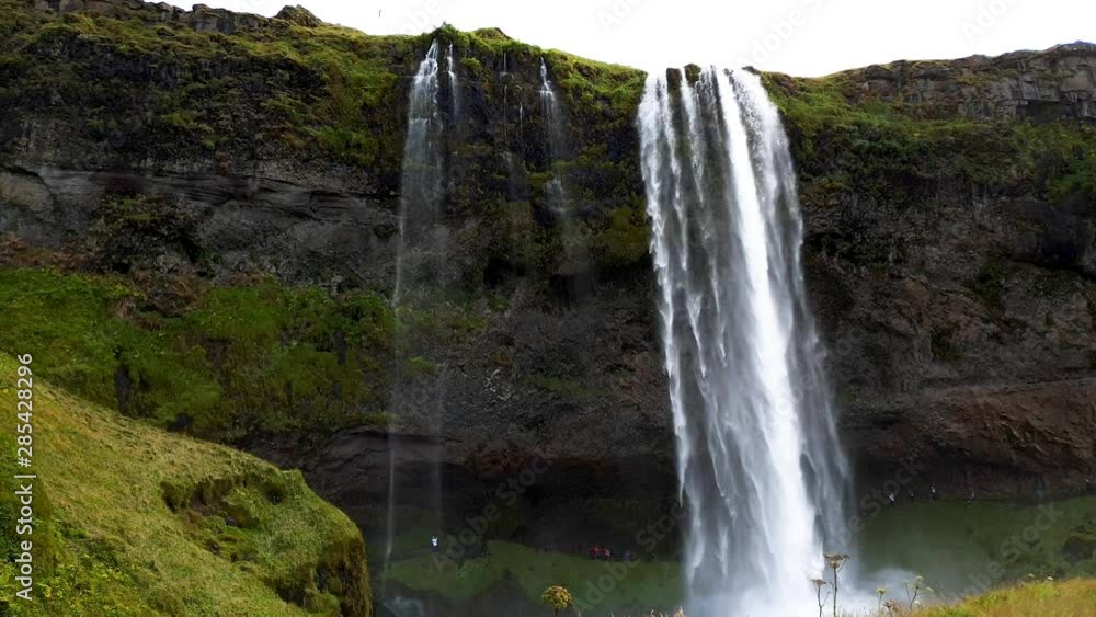 Merkjarfoss Gluggafoss Iceland Waterfall, low angle motion timelapse with people walking behind the waterfall