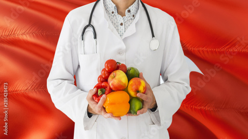 Doctor is holding fruits and vegetables in hands with Hong Kong flag background. National healthcare concept, medical theme.