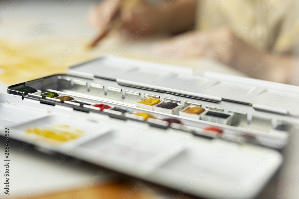 Close-up paint palette with blurred person Close-up paint palette with blurred person