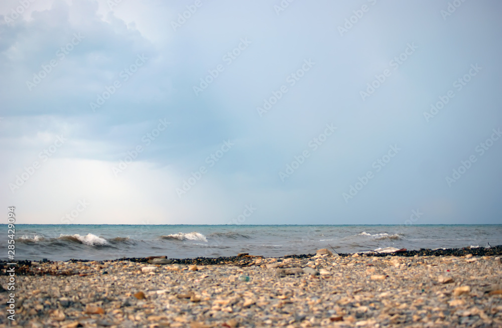 Cloudy day on the Black Sea. Pebble coast, sea, waves, cloudy sky.