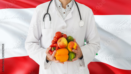 Doctor is holding fruits and vegetables in hands with Lebanon flag background. National healthcare concept, medical theme.