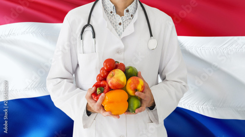 Doctor is holding fruits and vegetables in hands with Paraguay flag background. National healthcare concept, medical theme.