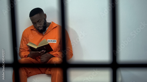 Fotografering African-american prisoner reading holy bible, convicted sinner, religion