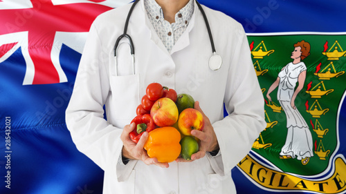 Doctor is holding fruits and vegetables in hands with British Virgin Islands flag background. National healthcare concept, medical theme.