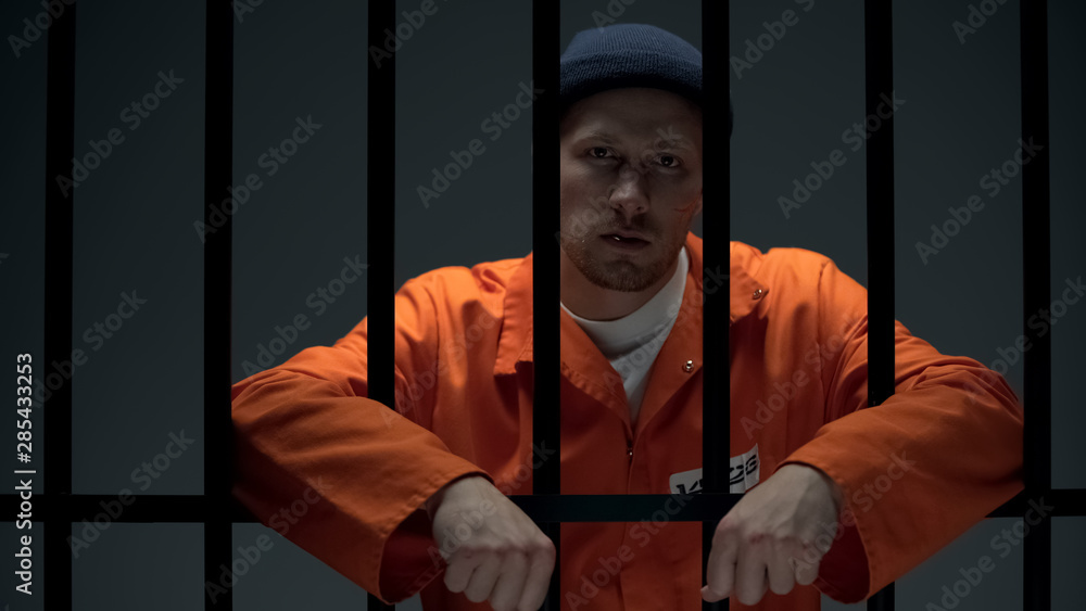 Dangerous imprisoned criminal splitting toothpick on floor and looking to camera