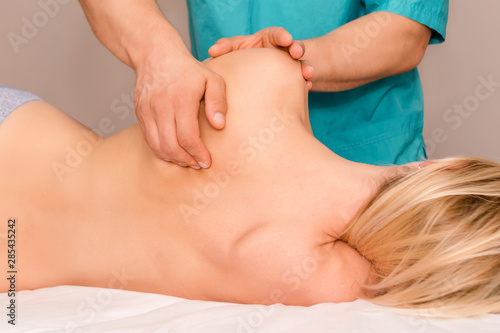 Woman having chiropractic back adjustment. Osteopathy, Alternative medicine, pain relief concept. Physiotherapist working with patient in clinic. Physiotherapy, sport injury rehabilitation.