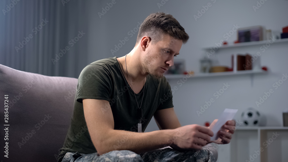Disappointed soldier looking at family photo, relationship problem, break-up Disappointed soldier looking at family photo, relationship problem, break-up