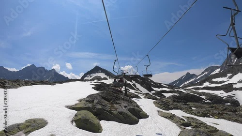 Small cable car in Alpine landscape after winter with melting snow on high rocky Austrian mountains.