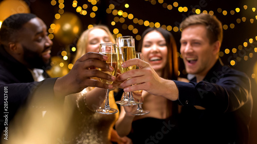 фотография Happy multi-ethnic company clinking beverage glasses, celebrating New Year