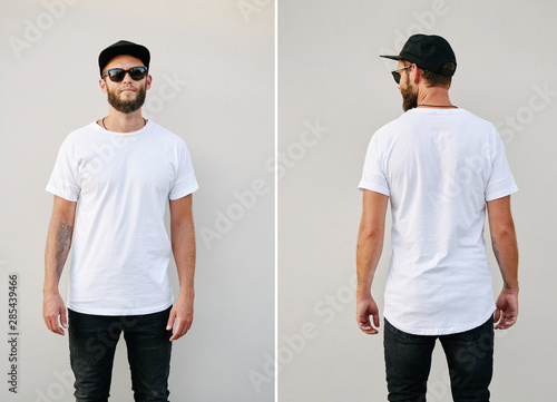 Hipster handsome male model with beard wearing white blank t-shirt and a baseball cap with space for your logo or design in casual urban style. Back and front view