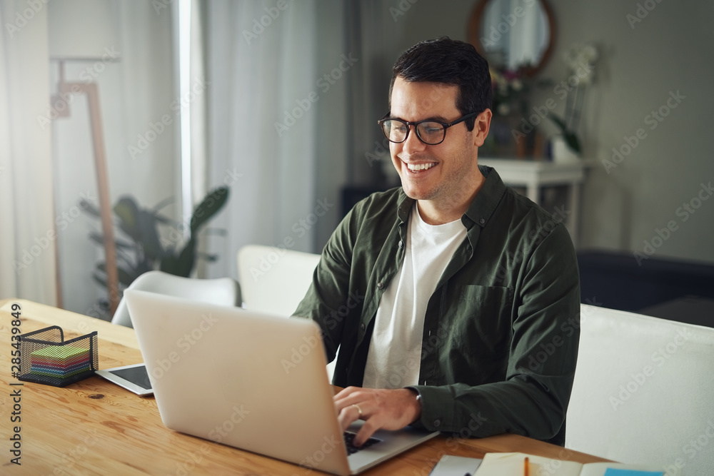 Happy man wearing eyeglasses using laptop at home Happy man wearing eyeglasses using laptop at home