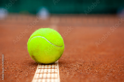 A yellow tennis ball lies on the clay court. © Dmytro Panchenko
