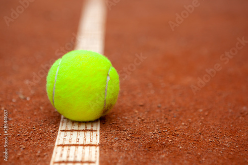 A yellow tennis ball lies on the clay court. © Dmytro Panchenko