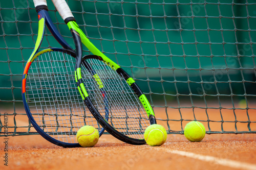 Tennis rackets and balls leaned against the net. © Dmytro Panchenko