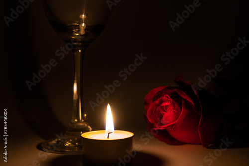 Tealight candle, wine glass and rose