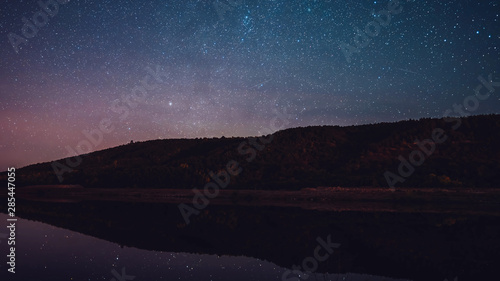 Starry sky over mountain and river at night.Constellations and planets 