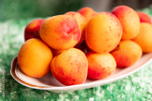 Ripe apricots in a plate on a green background