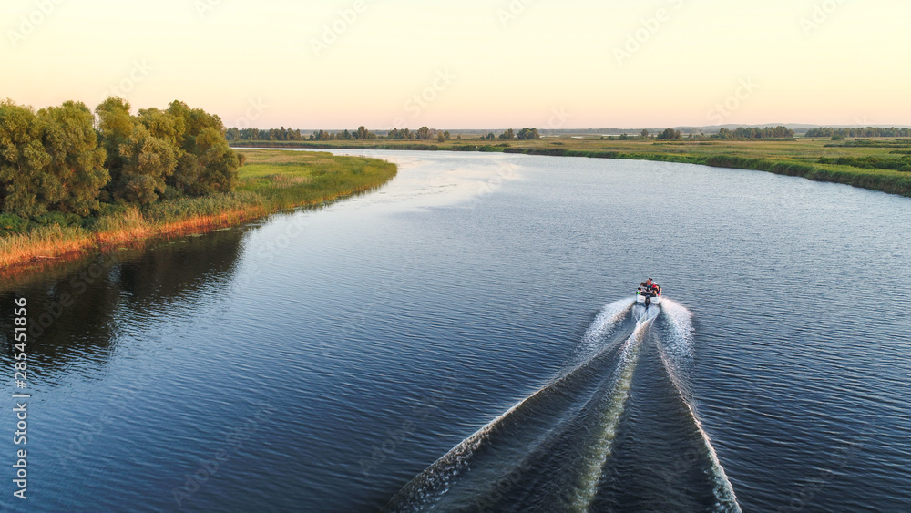 Aerial view of speed boat going on sunset on blue river 