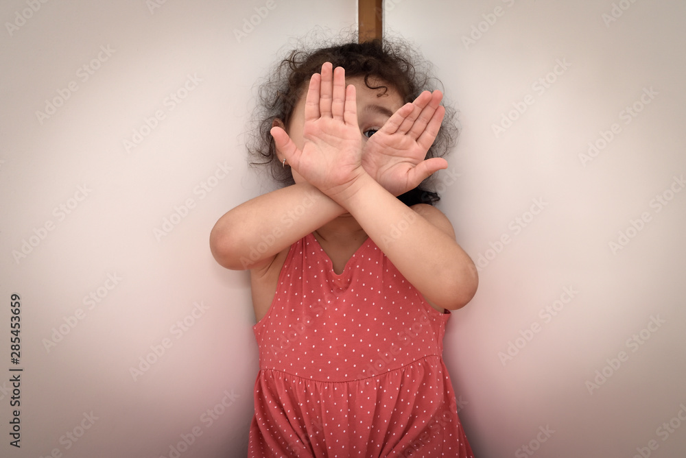Tight cropped face of a scared young girl with hands covering