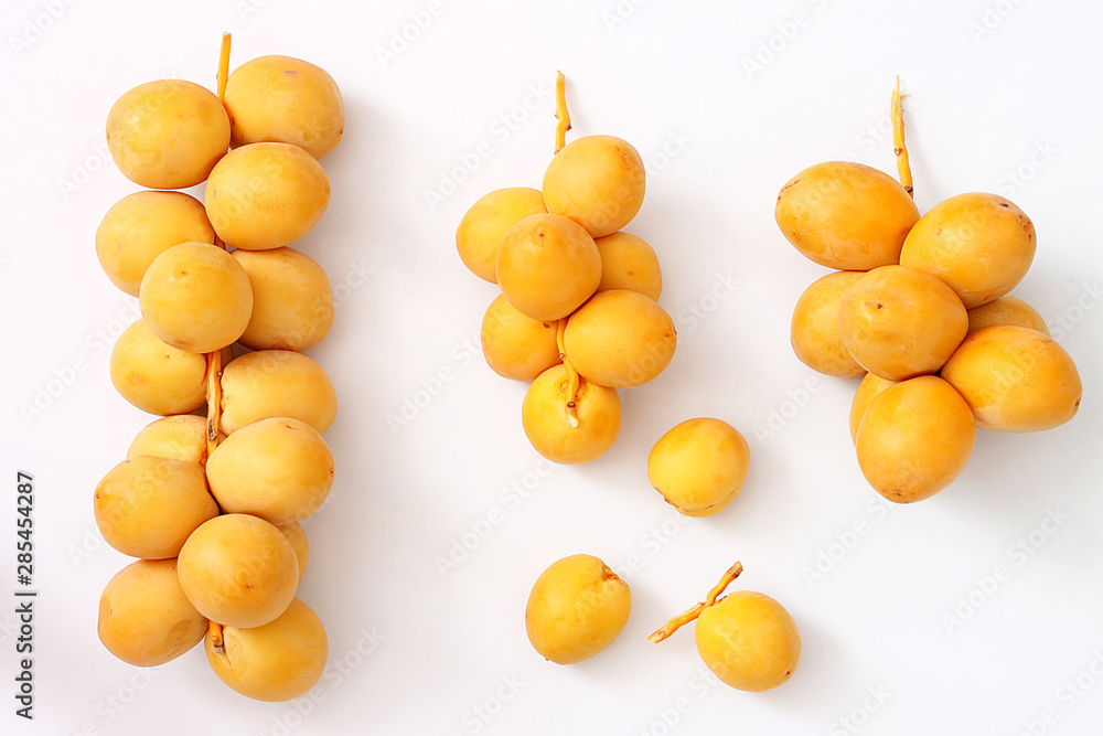 A bunch of yellow raw dates on a white background