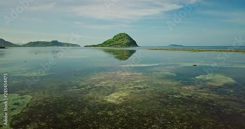 Aerial top view of agar-agar farm in ocean near tropical sand beach during low tide. Clear water and beautiful reef drone shot. Bird's eye view of poor asian agar garden bed from above.