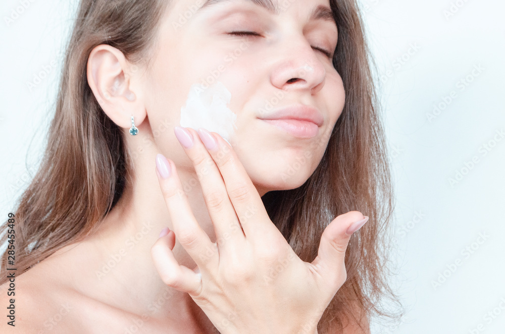 Beauty concept, beauty portrait of young woman with cream on cheek. Beauty concept, beauty portrait of young woman with cream on cheek.