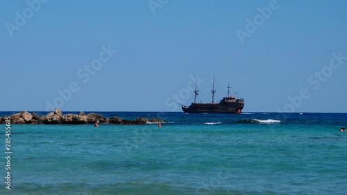 Stylized as a pirate ship, floating in the turquoise blue sea with white lamb and rocks
