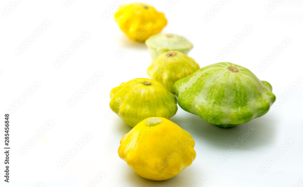 Pattypan squashes vegetable. Group of green and yellow pattypan squashes, on white table background. Pattypan squashes vegetable. Group of green and yellow pattypan squashes, on white table background.