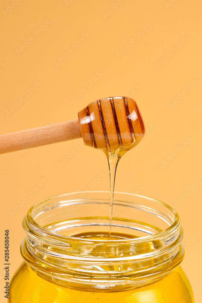 Dipper with honey in woman hand on orange background. Space for text or design. Dipper with honey in woman hand on orange background. Space for text or design.