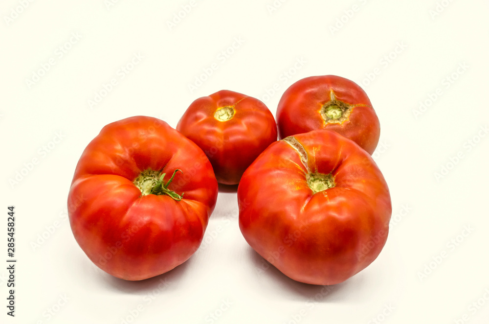 Summer harvest of very large and tasty red tomatoes grown in Armenia, lying on a white background Summer harvest of very large and tasty red tomatoes grown in Armenia, lying on a white background