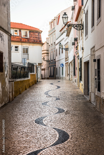 Narrow cobblestone alley between whitewashed houses in Cascais  Portugal