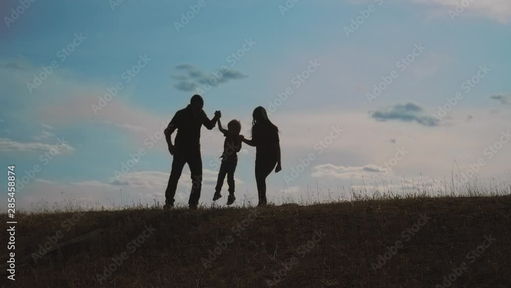 happy family father, mother and son outdoors silhouette concept slow motion video. dad man mom girl hold little boy son by hands. little boy jumping silhouette at sunset outdoors. happy family happy family father, mother and son outdoors silhouette concept slow motion video. dad man mom girl hold little boy son by hands. little boy jumping silhouette at sunset outdoors. happy family