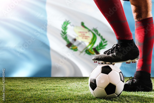 Obraz na plátně Close up legs of Guatemala football team player in red socks, shoes on soccer ball at the free kick or penalty spot playing on grass