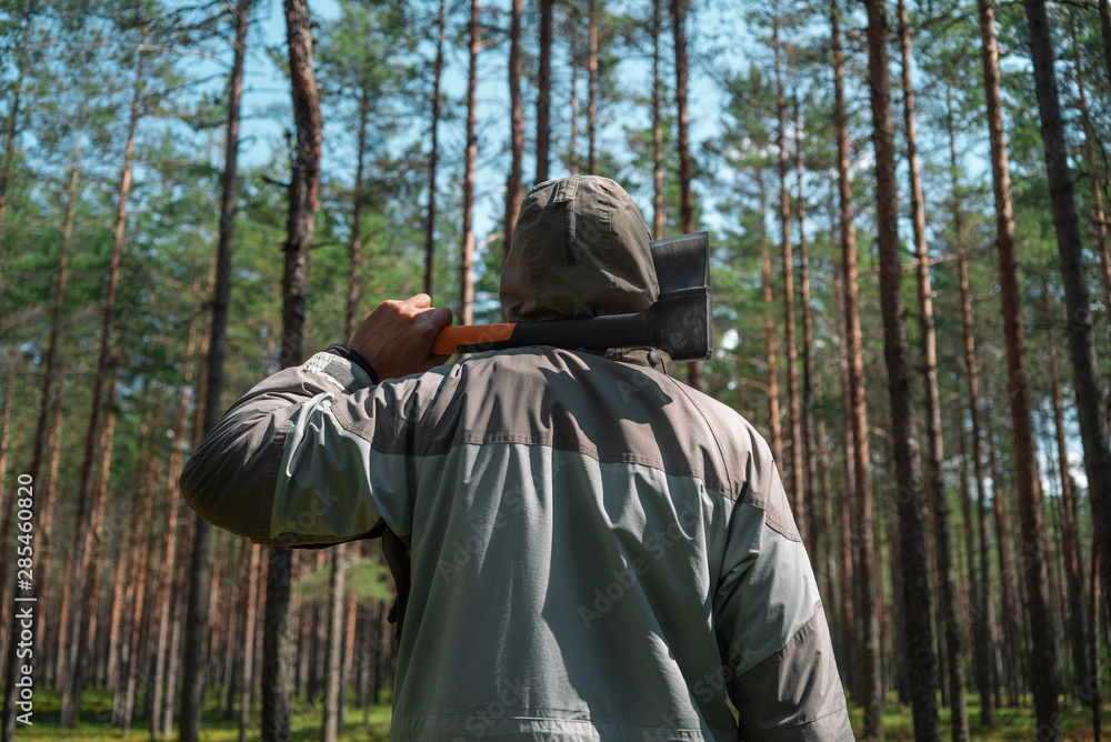 Lumberjack with an ax in the forest. View from the back. Lumberjack with an ax in the forest. View from the back.
