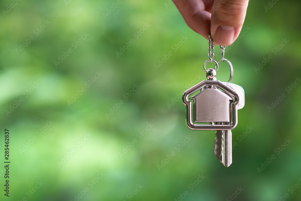 Home key with house keyring hanging with white wall background Home key with house keyring hanging with white wall background
