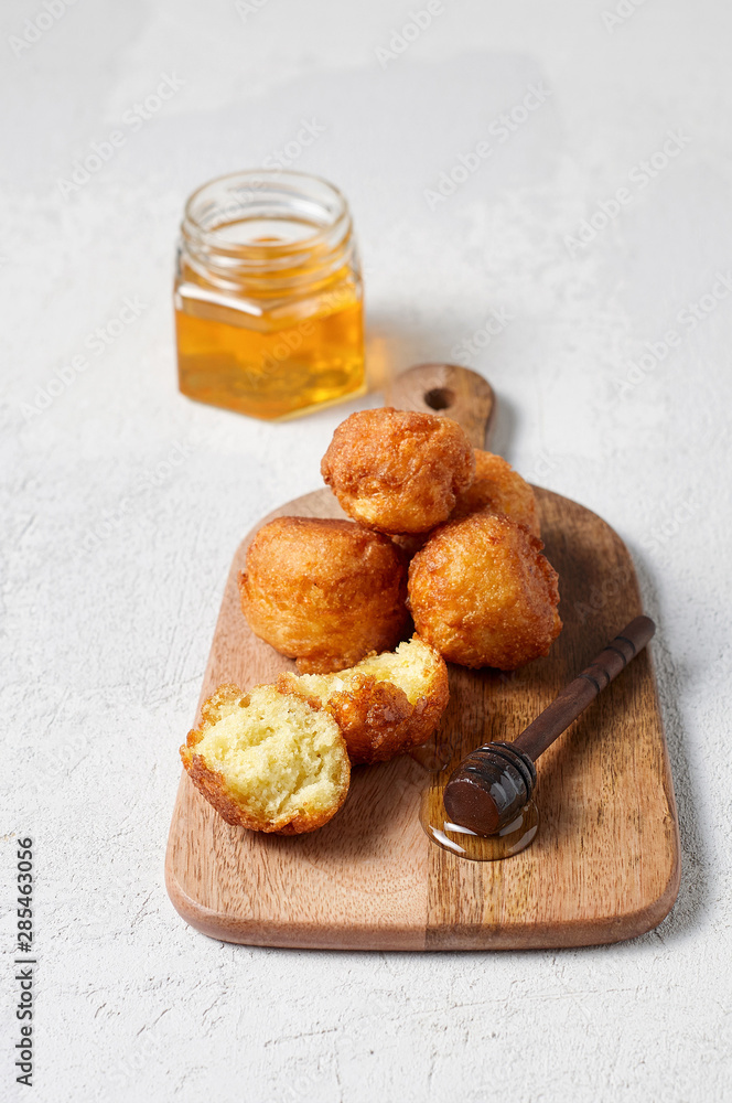 Cottage cheese balls doughnuts is jam-packed with jelly filling on wooden cut board and glass jar honey